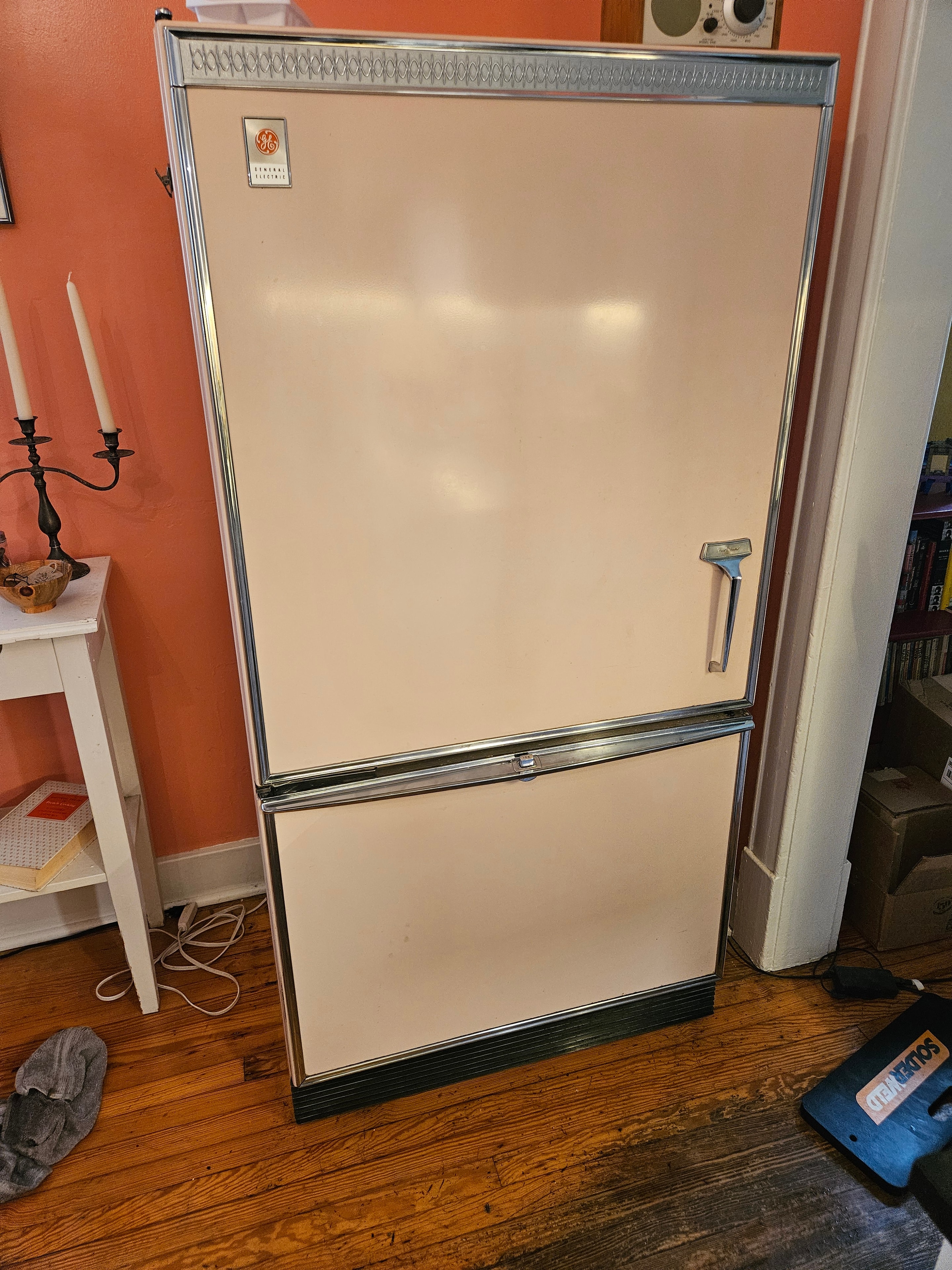 Technician accessing vintage GE refrigerator defrost system components during repair — Highlands Denver
