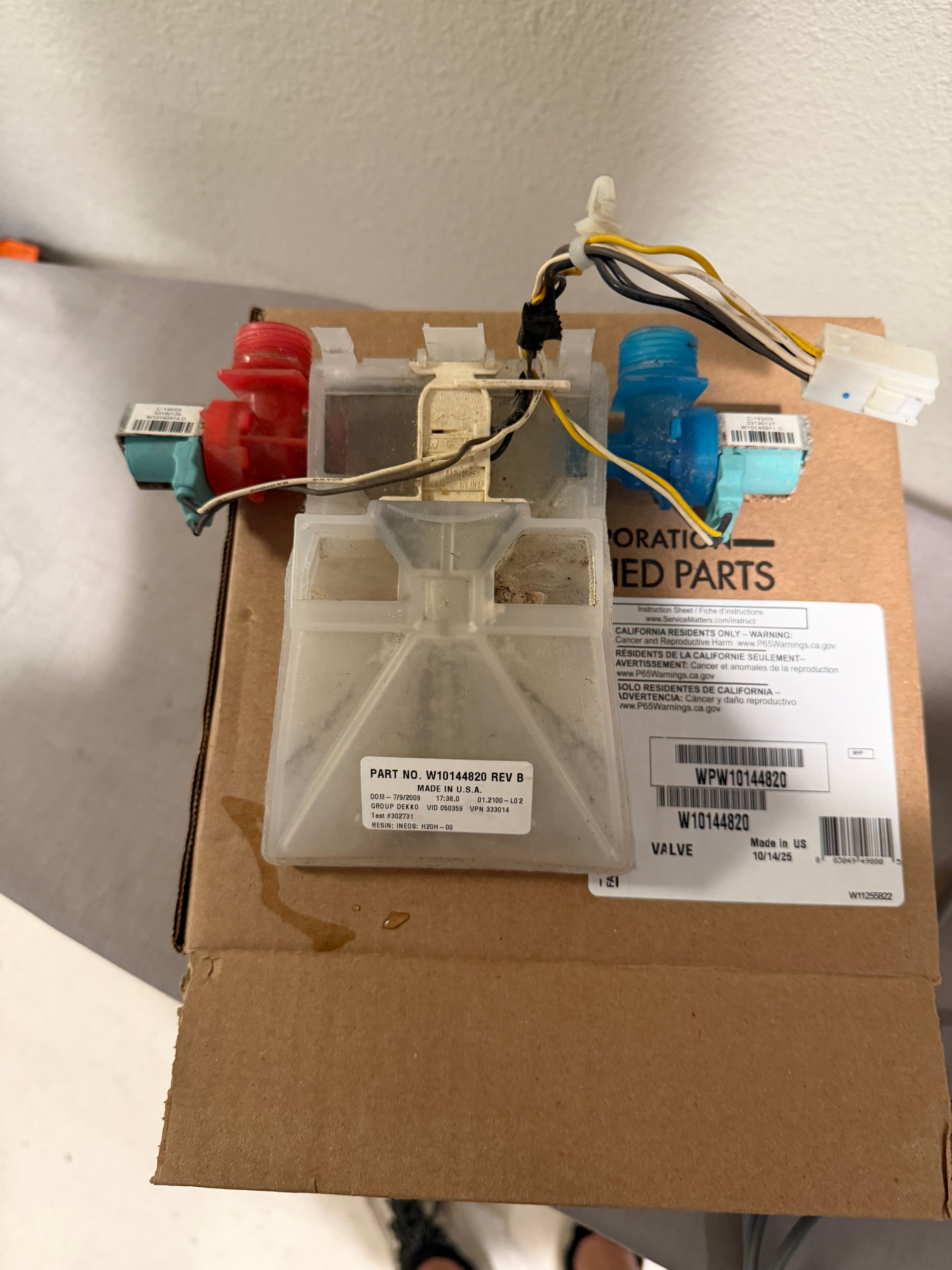 Original Whirlpool washer water inlet valve beside replacement packaging for WPW10144820